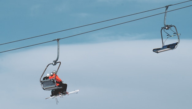 Tiro de ángulo bajo de personas en un teleférico bajo el hermoso cielo azul