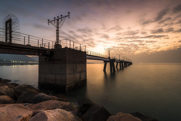 Tiro de ángulo bajo de un puente colgante sobre el hermoso océano capturado al atardecer