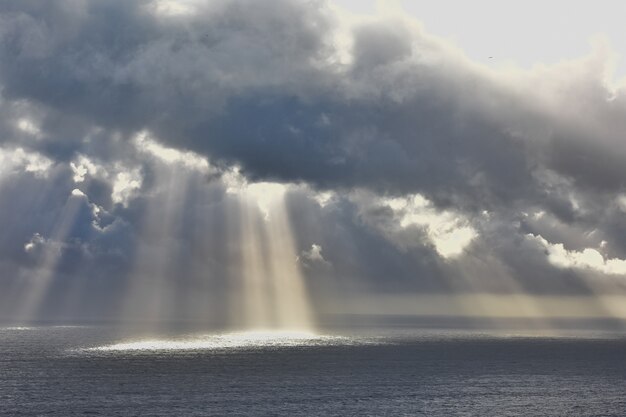 Tiro de ángulo bajo del sol brillando a través de las nubes sobre el hermoso océano