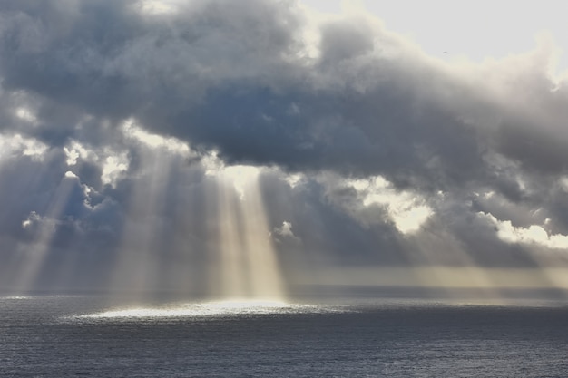 Tiro de ángulo bajo del sol brillando a través de las nubes sobre el hermoso océano