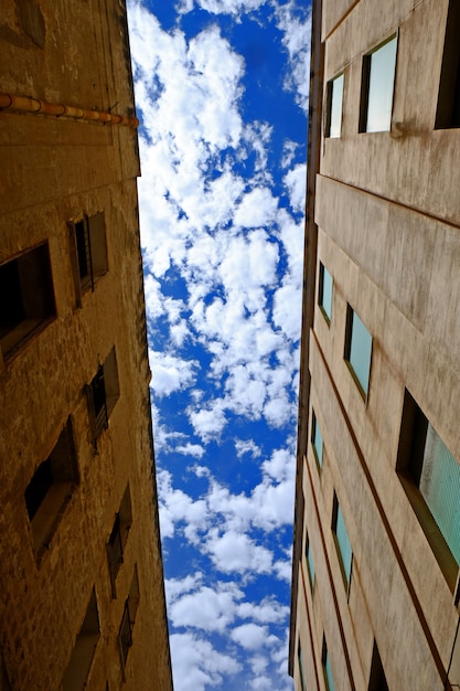 Tiro de ángulo bajo vertical entre dos edificios con cielo nublado