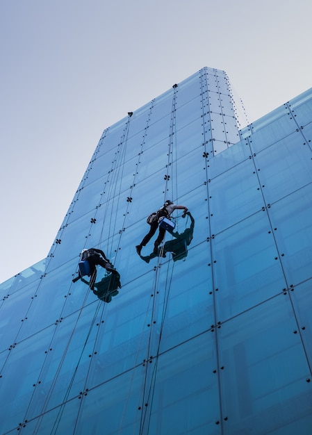 Tiro de ángulo bajo vertical de dos personas subiendo un edificio de cristal durante el día