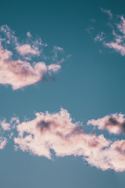 Foto gratuita tiro de ángulo bajo vertical de las magníficas nubes esponjosas en el cielo azul