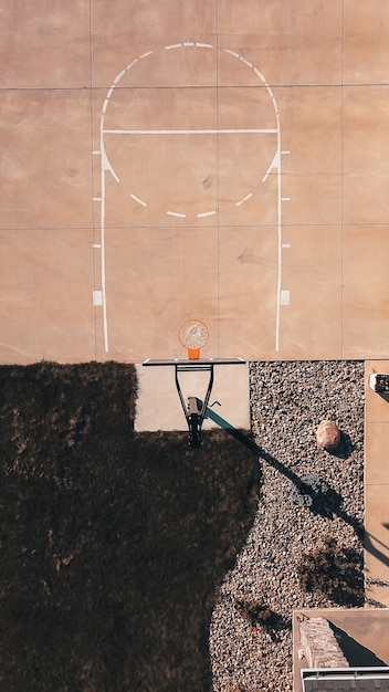 Foto gratuita tiro de arriba de un campo de baloncesto de cemento con el aro y las rocas