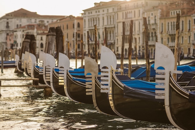 Foto gratuita tiro cercano de barcos cerca del muelle en el agua con edificios borrosos en el fondo durante el día