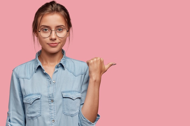 Foto gratuita tiro de cintura para arriba de mujer de aspecto agradable en gafas