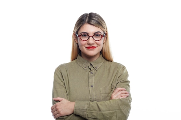 Foto gratuita tiro de cintura para arriba de positivo atractivo joven empleada o estudiante europea vistiendo lápiz labial rojo y gafas ovaladas sonriendo con confianza, manteniendo los brazos cruzados, posando aislado