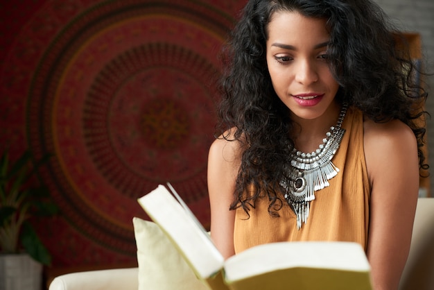 Tiro de cintura de atractiva mujer latina leyendo un libro