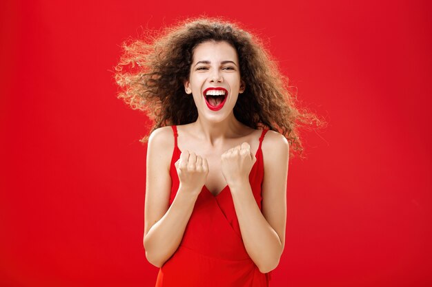 Tiro de cintura de éxito feliz mujer feliz contenta y encantada con el pelo rizado en elegante vestido apretar ...