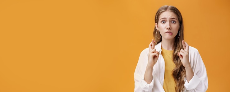 Foto gratuito tiro de cintura de mujer joven linda preocupada y emocionada en blusa sobre camiseta con pelo largo ondulado biti