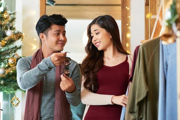 Tiro de la cintura de la pareja asiática de compras mirando las gafas de sol