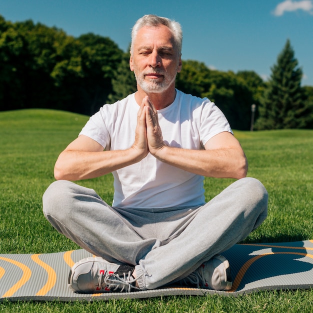 Foto gratuita tiro completo anciano meditando al aire libre