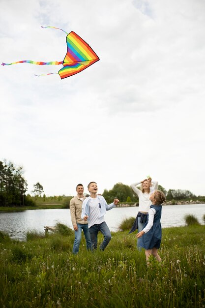 Tiro completo familia feliz volando cometa fuera