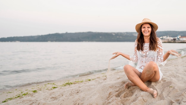 Tiro completo feliz mujer sentada en la orilla