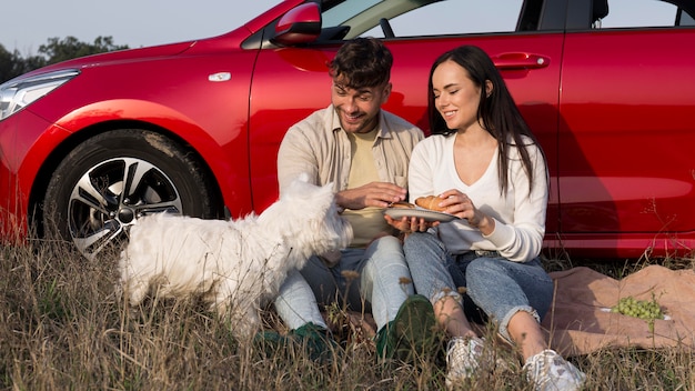 Foto gratuita tiro completo feliz pareja comiendo con perro