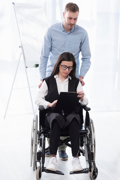 Foto gratuita tiro completo hombre ayudando a mujer en silla de ruedas