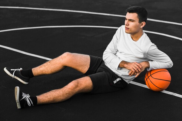 Tiro completo hombre descansando sobre baloncesto