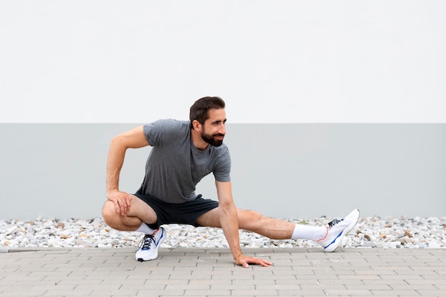 Tiro completo hombre estirando al aire libre