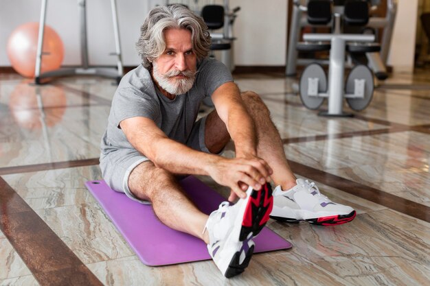 Tiro completo hombre estirando en el gimnasio