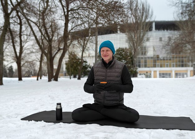 Foto gratuita tiro completo hombre sentado en la estera de yoga