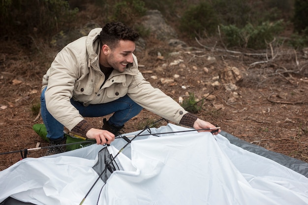 Foto gratuita tiro completo hombre sonriente levantando una carpa