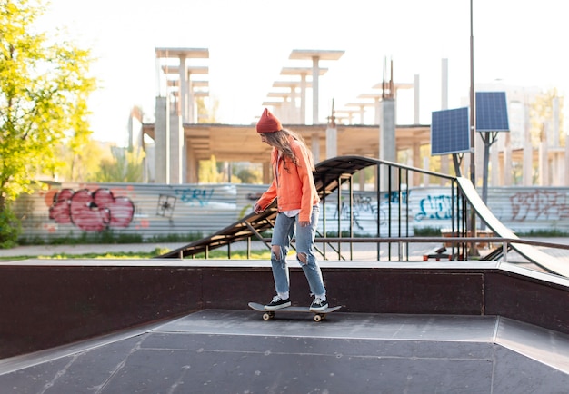 Foto gratuita tiro completo joven en patineta fuera