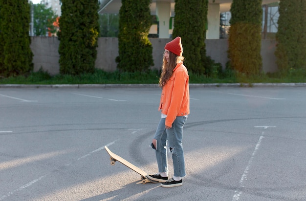 Foto gratuita tiro completo joven con skate al aire libre