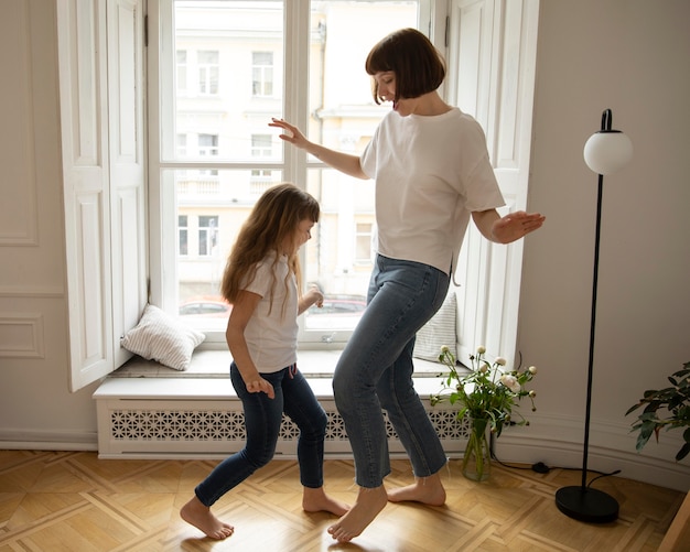 Foto gratuita tiro completo madre y niña bailando en el interior