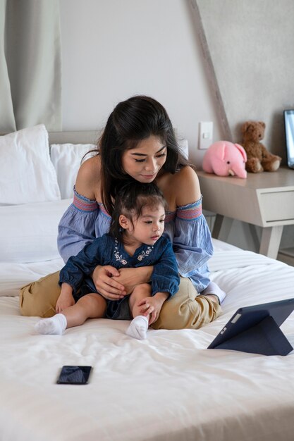 Tiro completo madre y niña mirando tableta