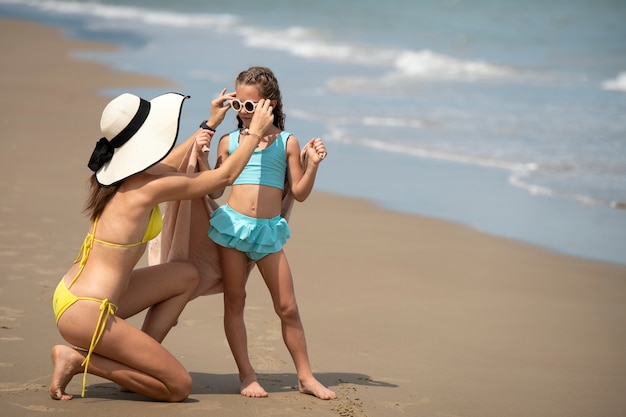 Tiro completo madre y niña en la playa