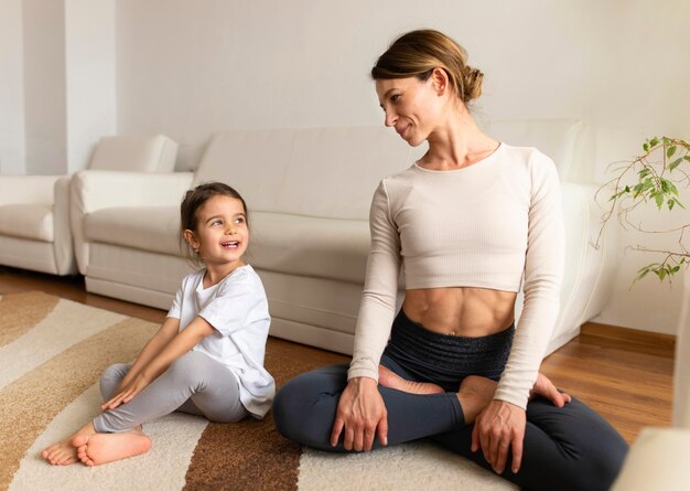 Tiro completo madre y niña sentada en el piso