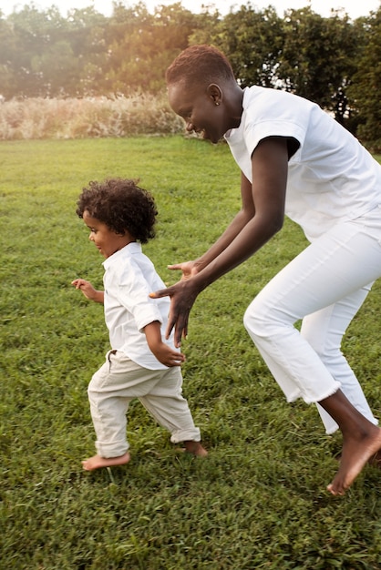 Foto gratuita tiro completo madre y niño corriendo al aire libre