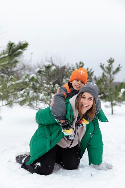 Tiro completo madre y niño jugando con nieve.