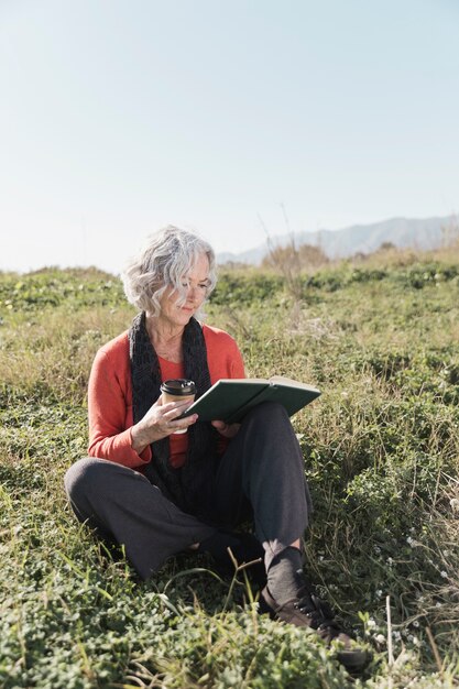 Tiro completo mujer con café y libro al aire libre