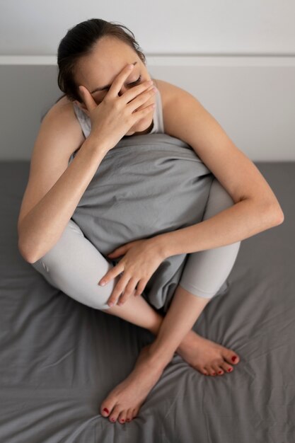 Tiro completo mujer deprimida sosteniendo la almohada