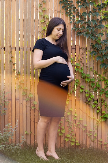 Foto gratuita tiro completo mujer embarazada en vestido negro posando