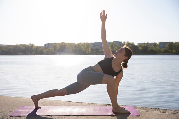 Tiro completo mujer estirando sobre estera de yoga