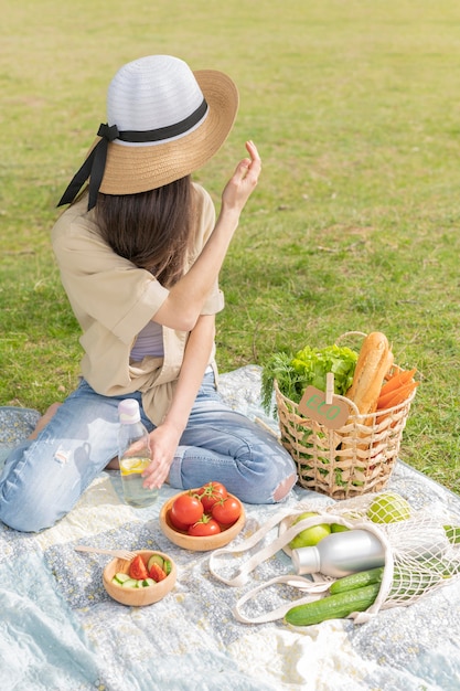 Foto gratuita tiro completo mujer haciendo picnic mirando a otro lado