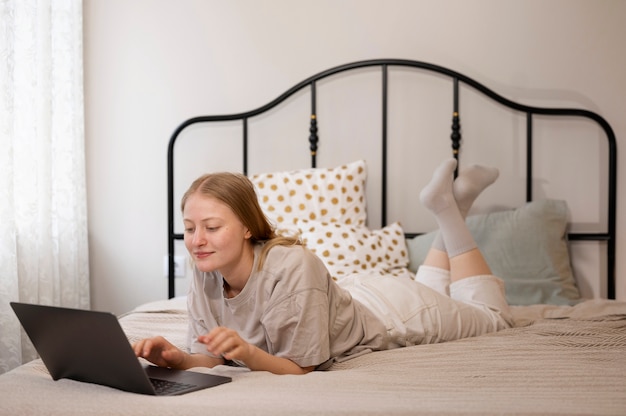 Tiro completo mujer con laptop en la cama