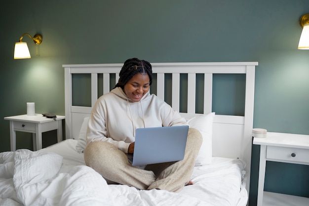 Tiro completo mujer con laptop en la cama