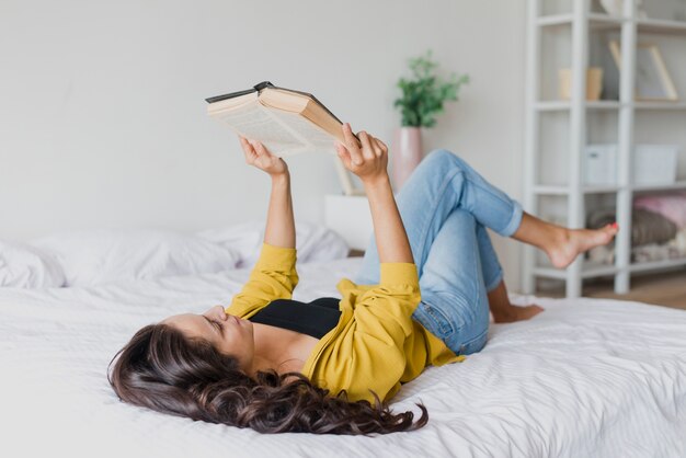 Tiro completo mujer leyendo en la cama