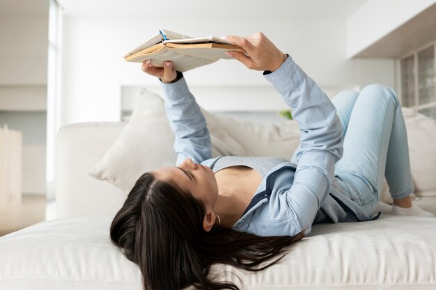 Tiro completo mujer leyendo en la cama