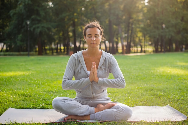 Tiro completo mujer meditando sobre estera de yoga