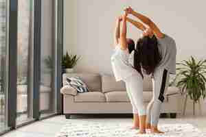 Foto gratuita tiro completo mujer y niña haciendo yoga