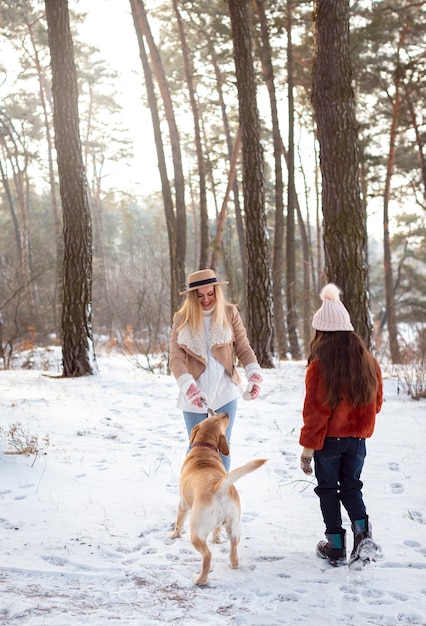 Tiro completo mujer y niña con perro.