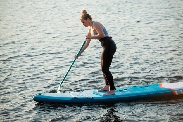 Tiro completo de mujer paddleboarding