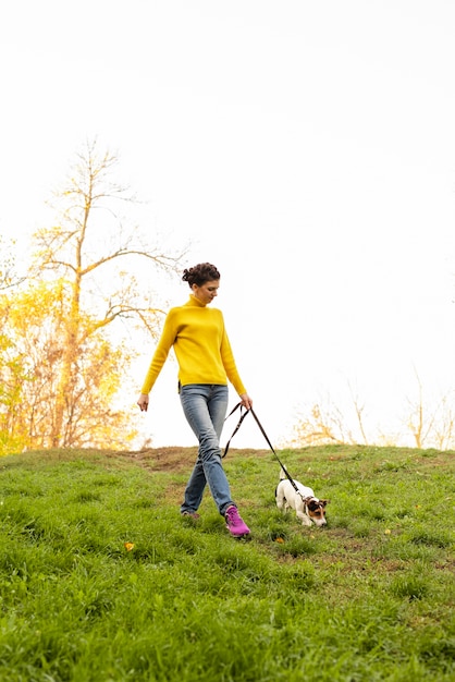 Foto gratuita tiro completo mujer paseando a su perro en el parque