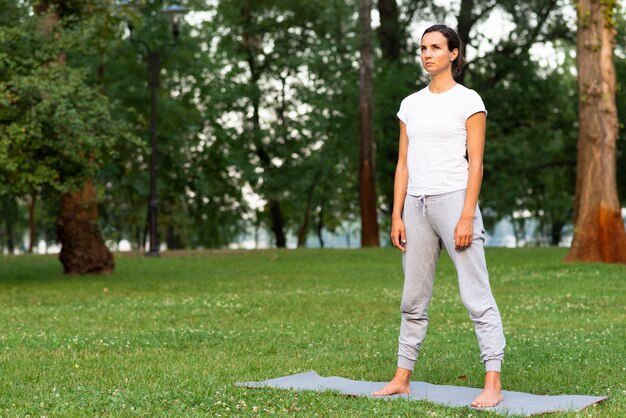 Tiro completo mujer de pie sobre estera de yoga