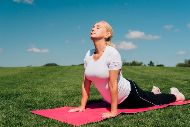 Tiro completo mujer en pose de yoga al aire libre