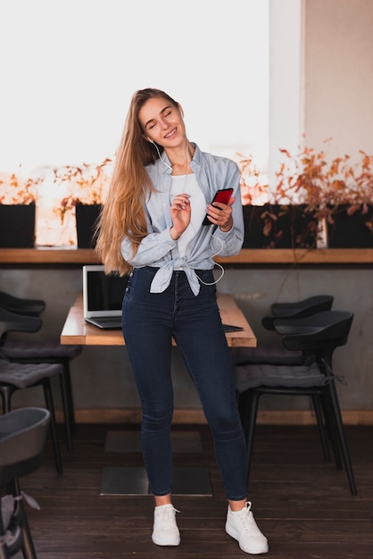 Foto gratuita tiro completo mujer rubia sosteniendo un teléfono